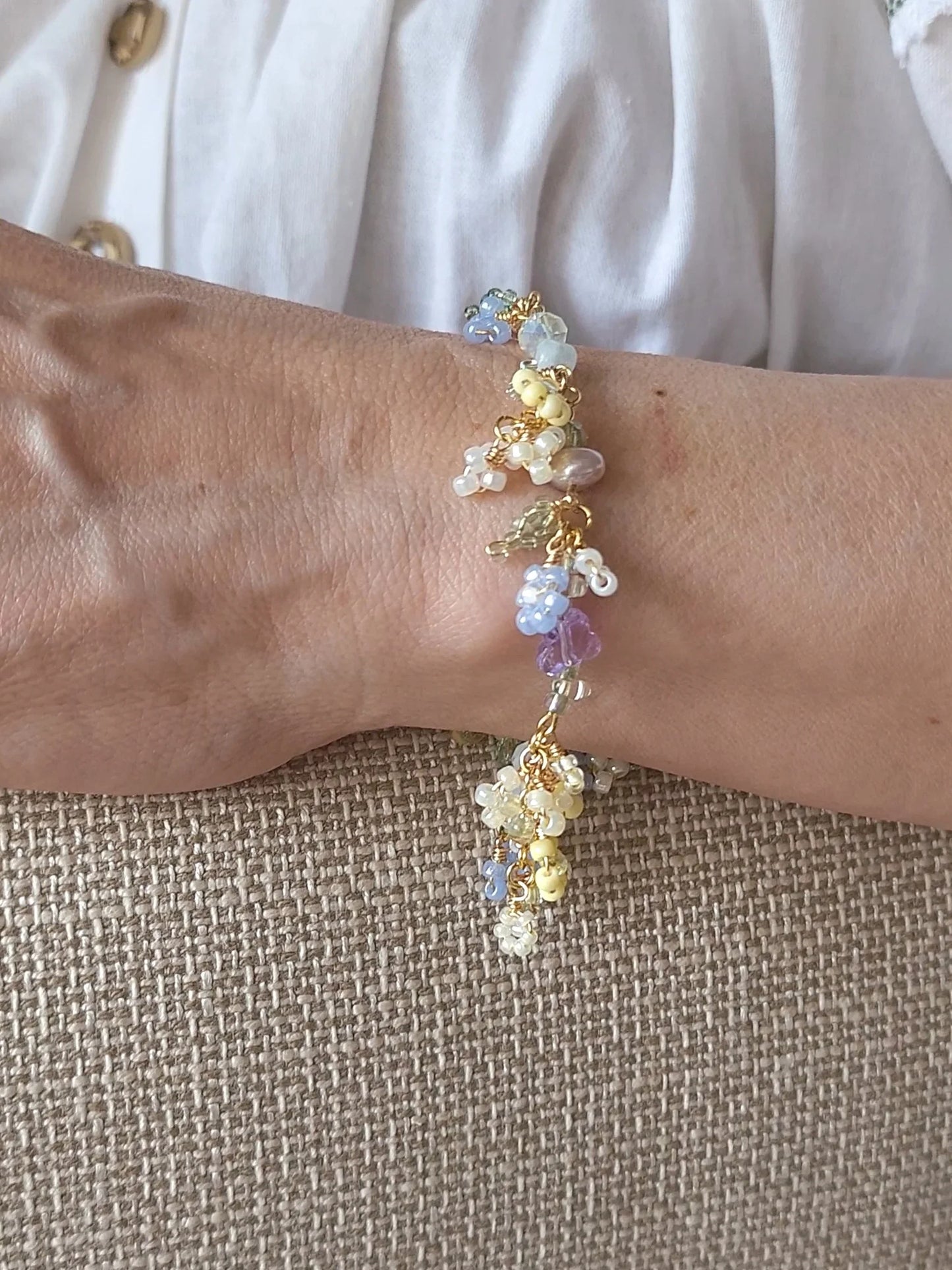 Close-up of a wrist wearing a colorful beaded bracelet on a textured beige surface.