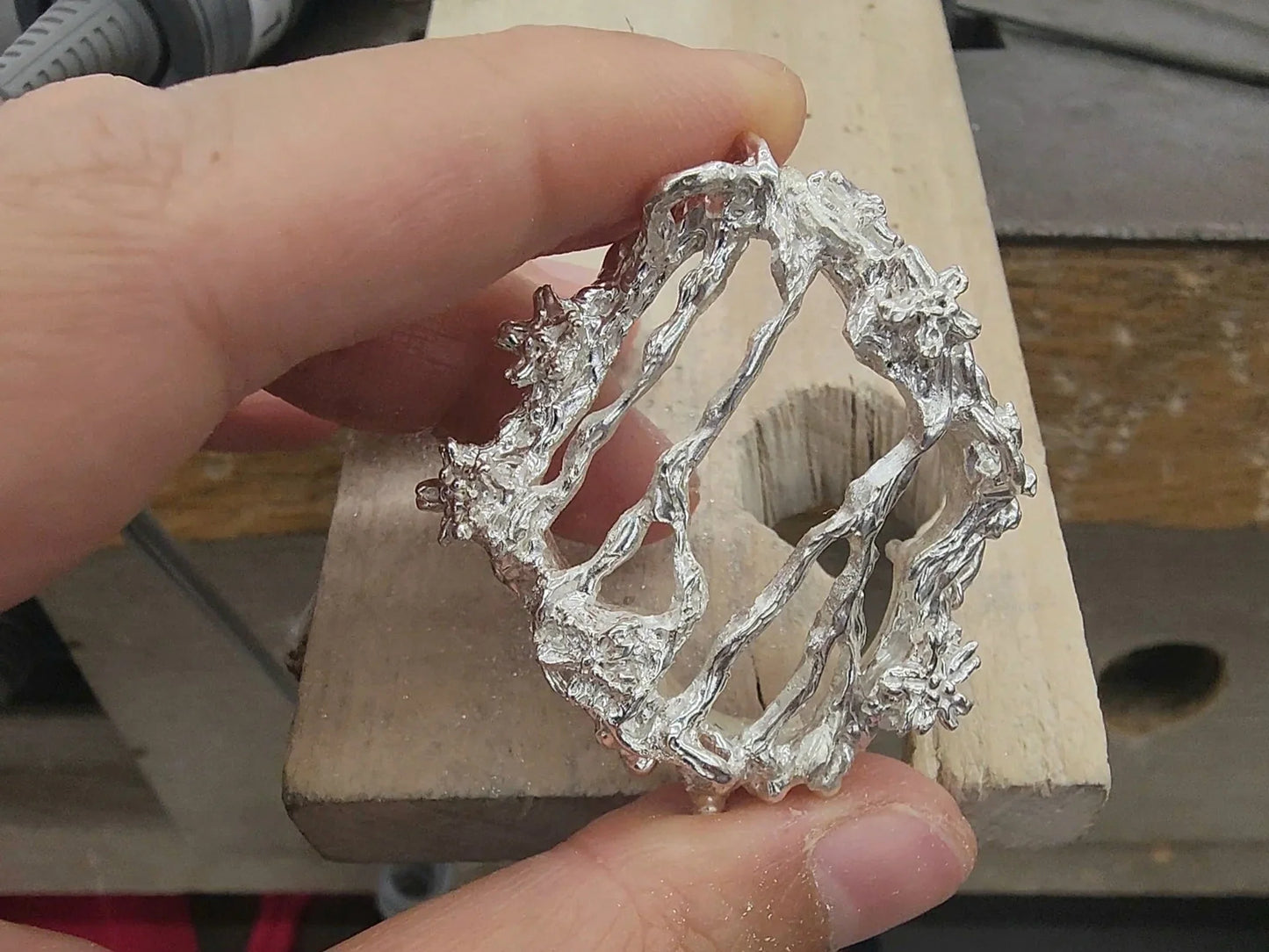 A jewelry artist is filing a silver piece.