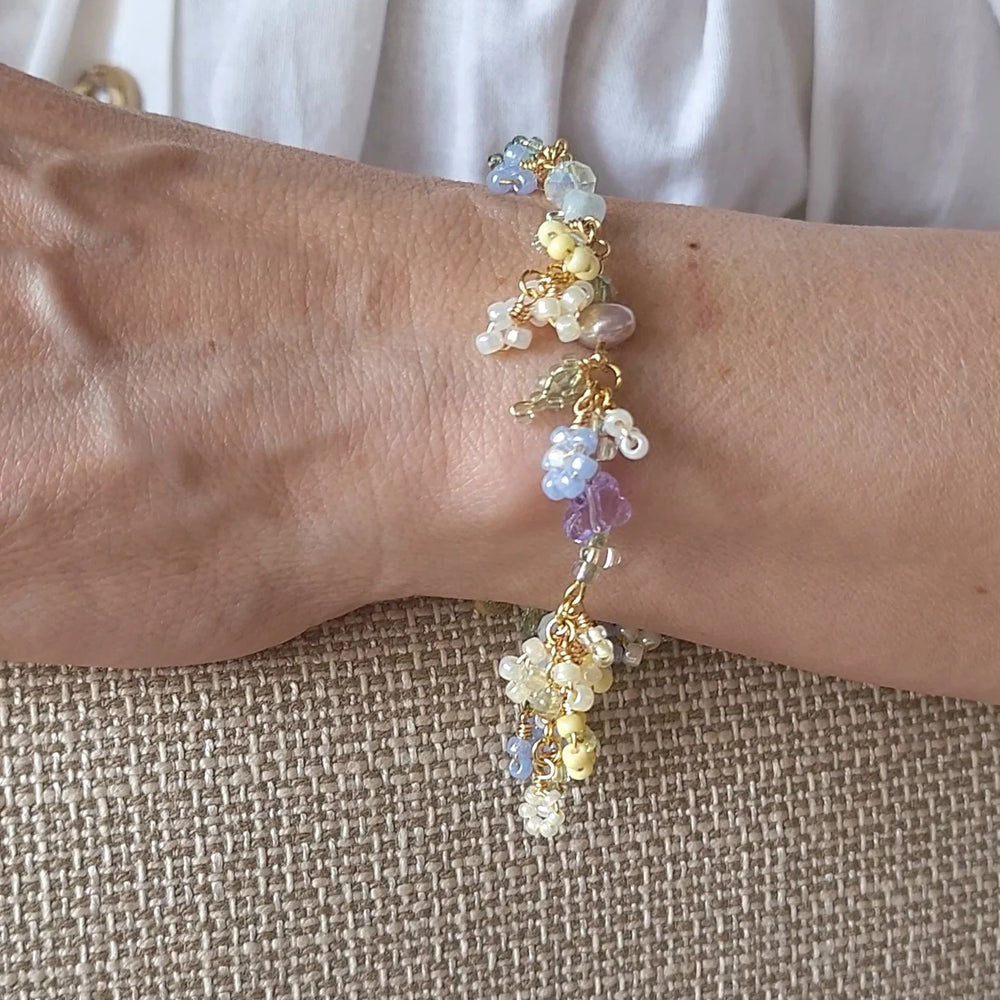 
                  
                    Close-up of a wrist wearing a colorful beaded bracelet on a textured beige surface.
                  
                