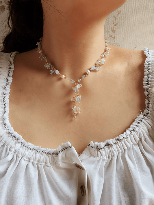 This handcrafted choker is composed of opalite, baby blue bugle beads, freshwater pearls, acrylic flower beads, seed beads, and gold-plated findings for an ethereal, soft, and detailed finish.