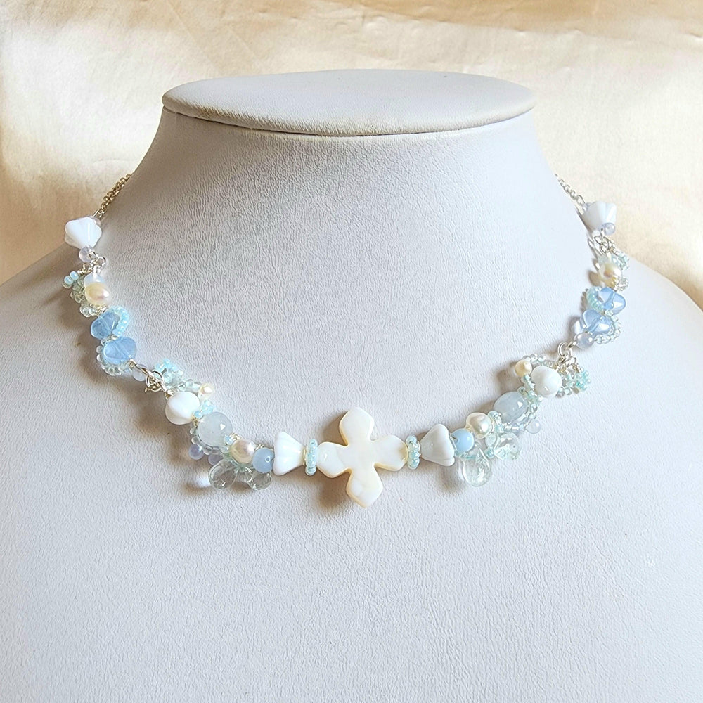 
                  
                    The Knights of the Sky are an esteemed class that traverse the skies, their silhouettes framed by the backdrop of white-tinted, petal-laden clouds. This handcrafted necklace is constructed with a shell centerpiece, vintage glass beads, Czech glass beads, freshwater pearls, and silver-plated accents.
                  
                