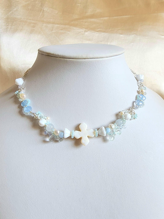 The Knights of the Sky are an esteemed class that traverse the skies, their silhouettes framed by the backdrop of white-tinted, petal-laden clouds. This handcrafted necklace is constructed with a shell centerpiece, vintage glass beads, Czech glass beads, freshwater pearls, and silver-plated accents.
