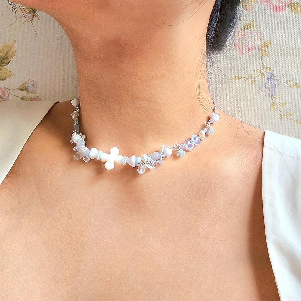 
                  
                    The Knights of the Sky are an esteemed class that traverse the skies, their silhouettes framed by the backdrop of white-tinted, petal-laden clouds. This handcrafted necklace is constructed with a shell centerpiece, vintage glass beads, Czech glass beads, freshwater pearls, and silver-plated accents.
                  
                