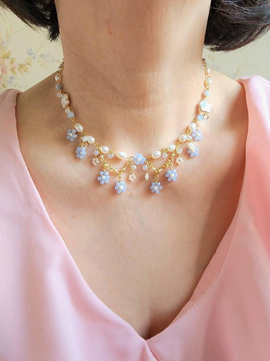 This timeless piece is comprised of freshwater pearls, glass beads and gold-plated findings, and intricately handcrafted to resemble Nemophila fields in bloom with its beaded flowers and white freshwater pearls symbolizing the expansive sky above.