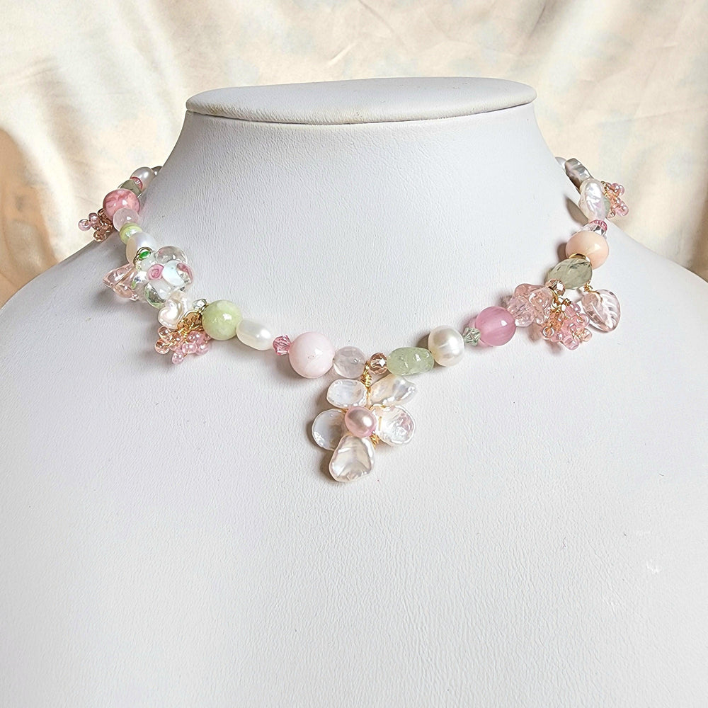 
                  
                    This beaded necklace boasts an array of freshwater pearls and gemstones, such as green aventurine, aquamarine, prehnite, pink opal, and rose quartz, together with lampworked glass beads and gold-plated findings for a vibrant, joyful look reminiscent of springtime.
                  
                