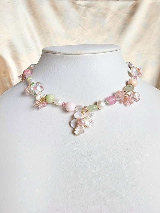 This beaded necklace boasts an array of freshwater pearls and gemstones, such as green aventurine, aquamarine, prehnite, pink opal, and rose quartz, together with lampworked glass beads and gold-plated findings for a vibrant, joyful look reminiscent of springtime.