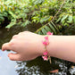 Red and Pink acrylic flowers are connected in bunches with green faceted glass beads in between to form a dainty tropical vibe bracelet.