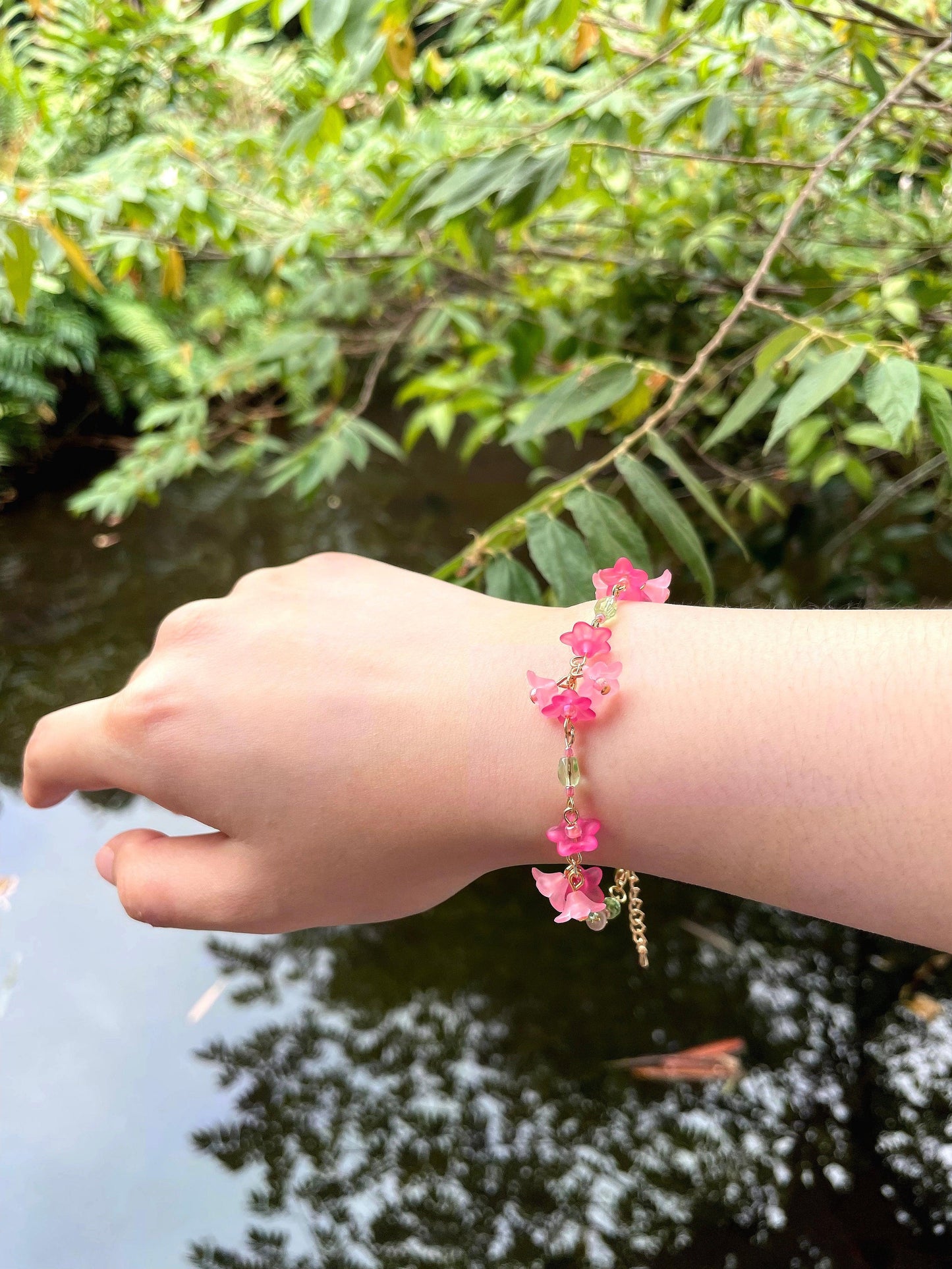 Red and Pink acrylic flowers are connected in bunches with green faceted glass beads in between to form a dainty tropical vibe bracelet.