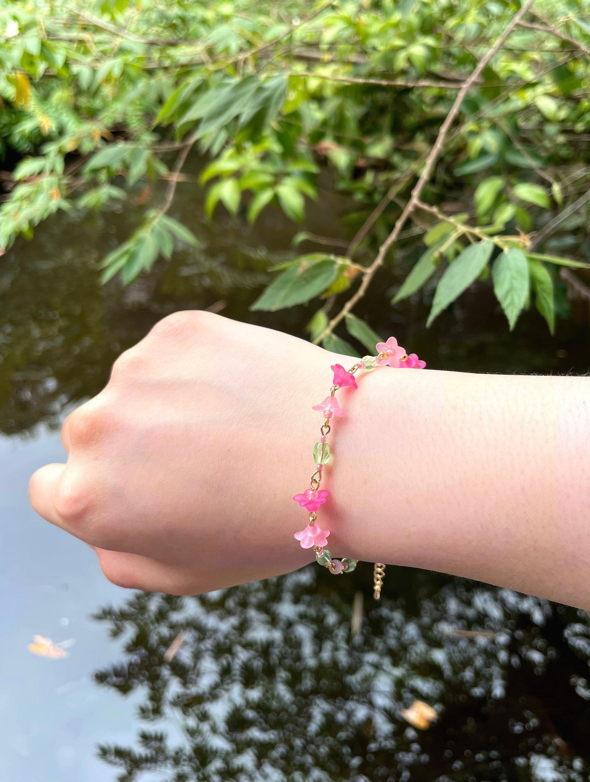 Red and Pink acrylic flowers are connected with green faceted glass beads in between to form a dainty tropical vibe bracelet.